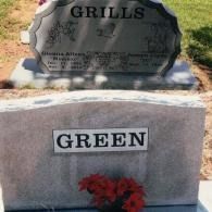 Two headstones in a grassy cemetery, one labeled 