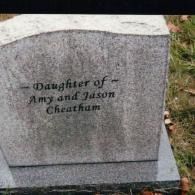 A gray granite headstone inscribed with the text, 