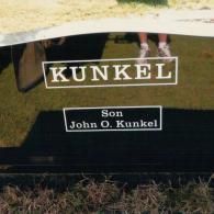 A polished black granite gravestone engraved with the text 