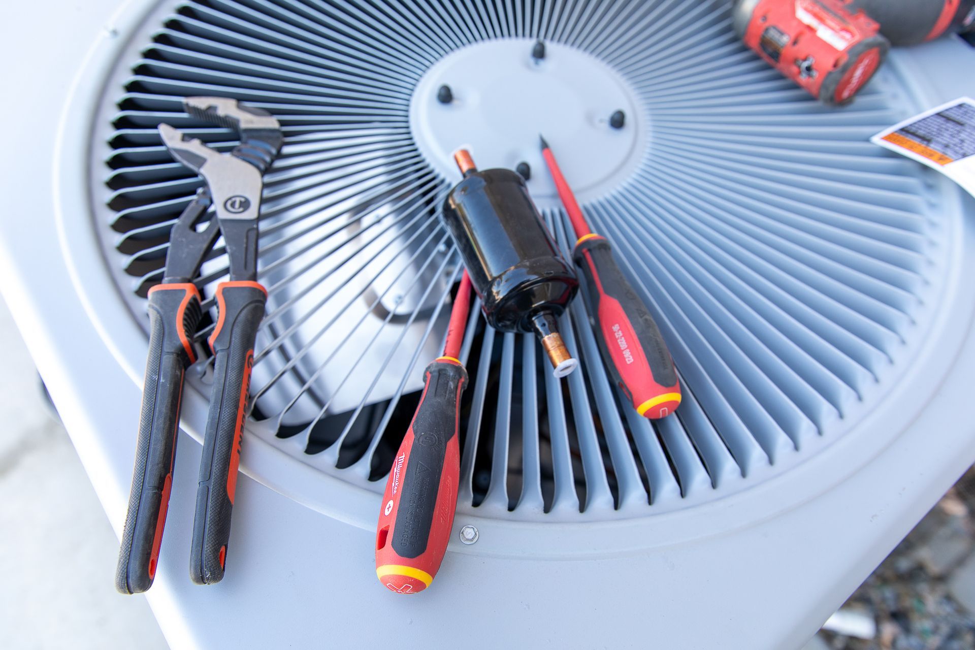 A pair of pliers sits on top of an air conditioner
