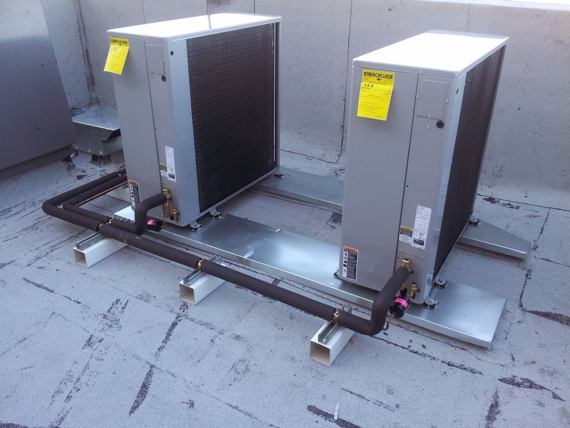 Two air conditioners are sitting on top of each other on a roof