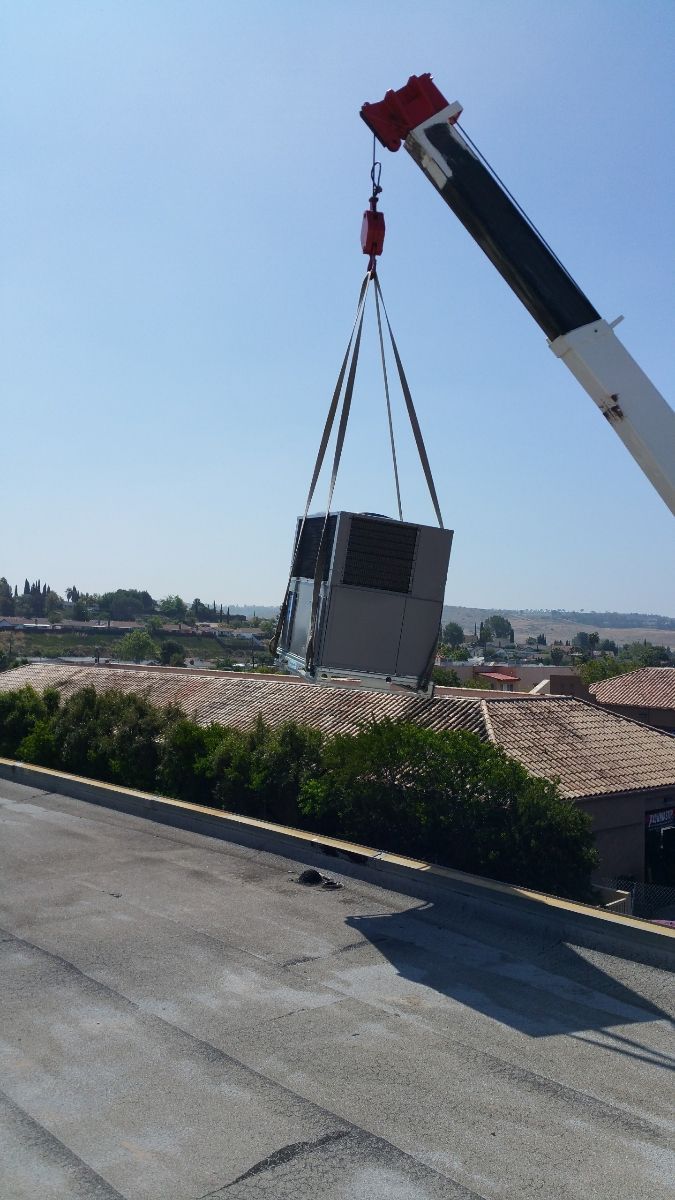 A crane is lifting a large piece of equipment into the air