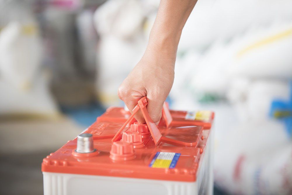 Man Carrying Car Battery — Automotive Batteries in Boonah, QLD