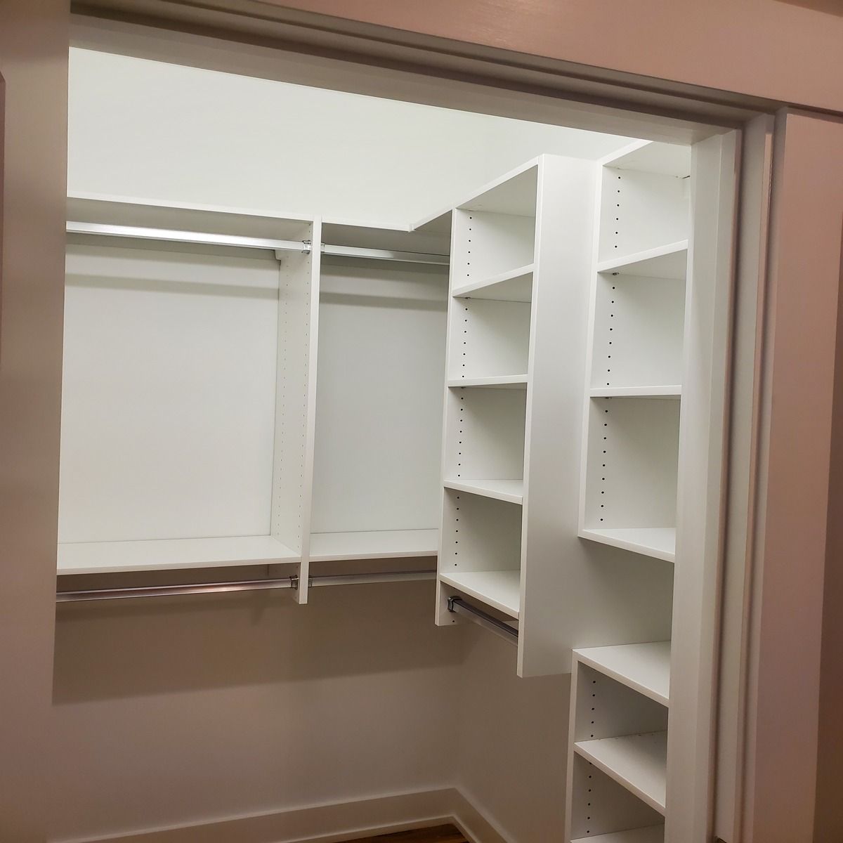 Empty walk-in closet with white shelving and a hanging rod, ready for clothes.