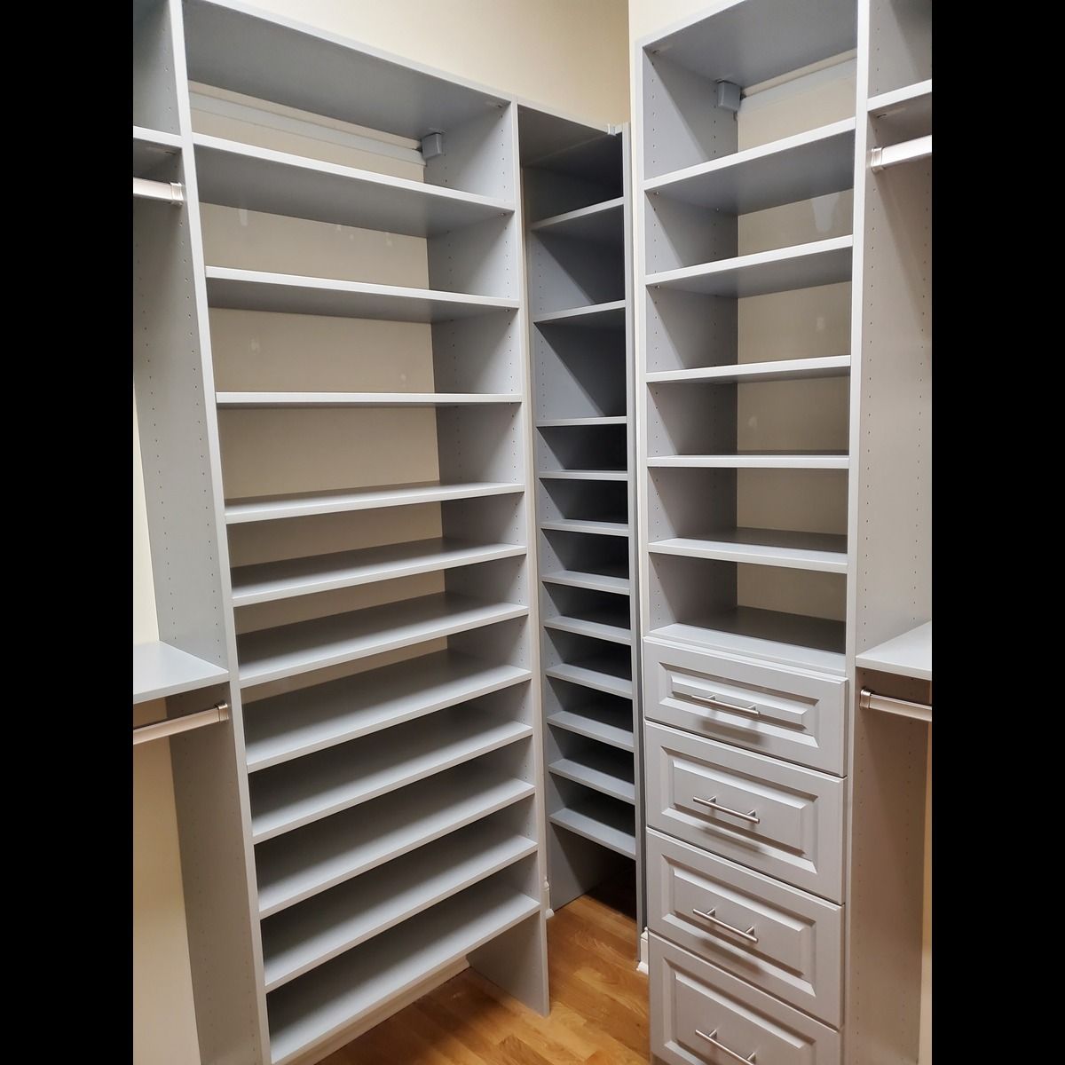 Gray closet shelving with multiple shelves and drawers. Built-in unit with a narrow center section.