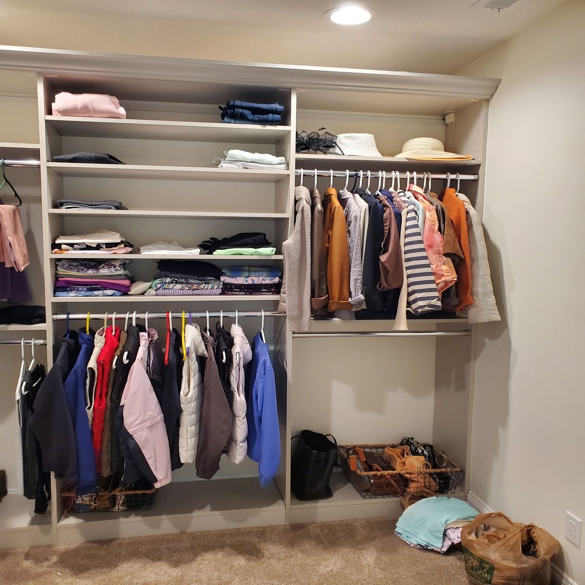 A walk-in closet with clothes hanging and folded on shelves, and a hat rack.