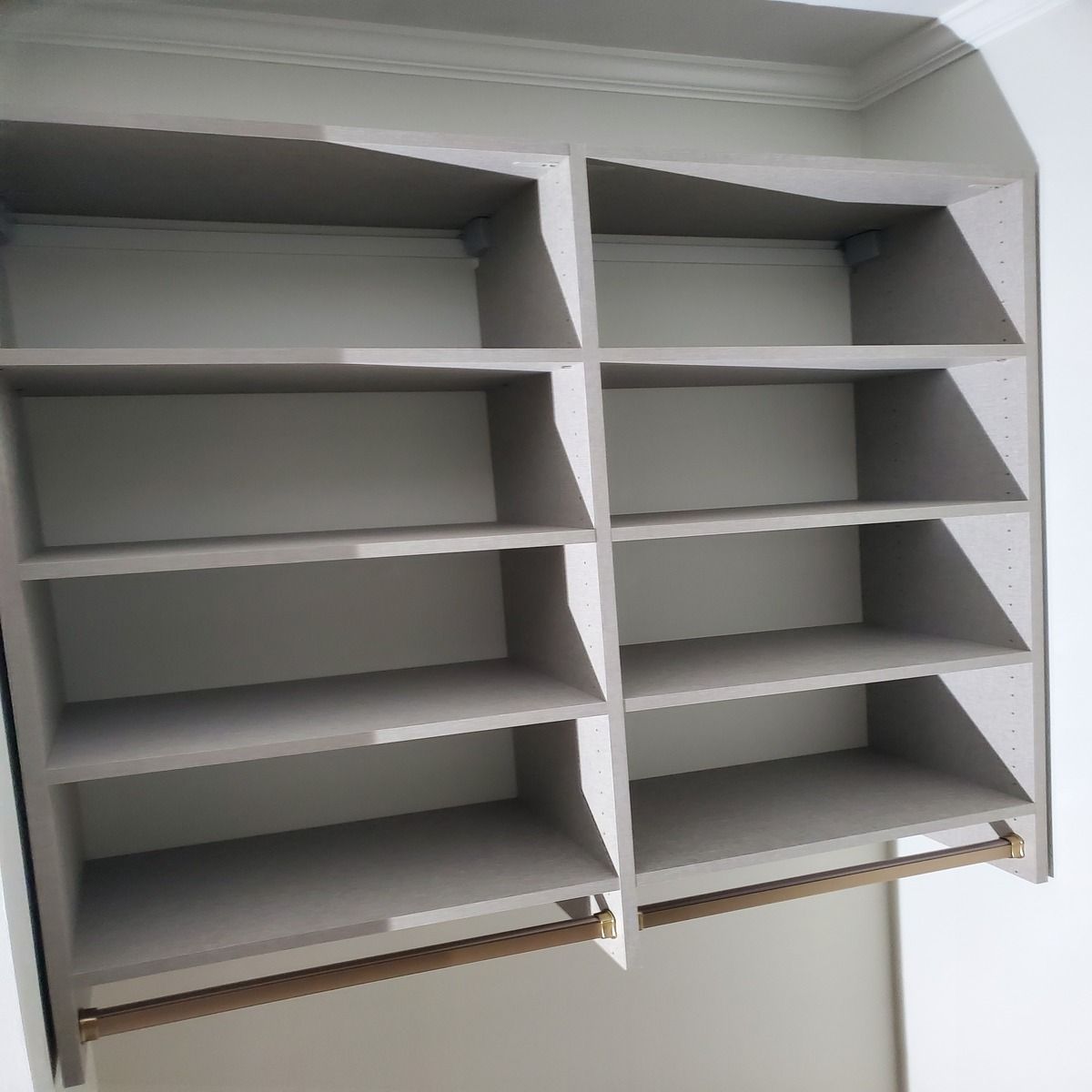 Built-in shelving unit with four shelves in each of two sections. Includes a brass-colored rod at the bottom.