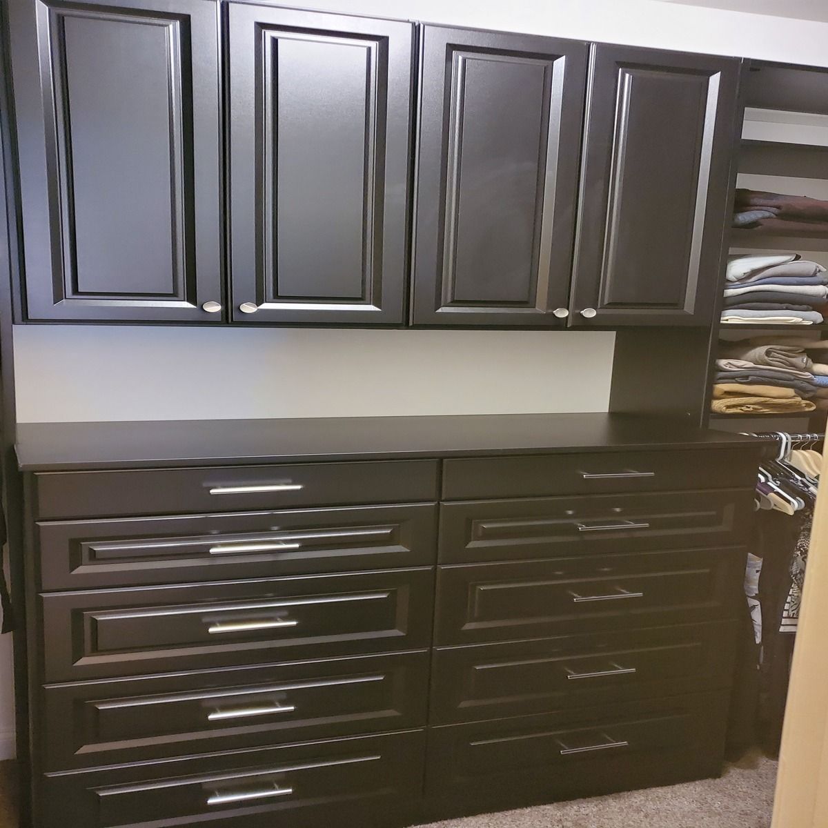 Dark brown closet organizer with overhead cabinets and multiple drawers, silver hardware.