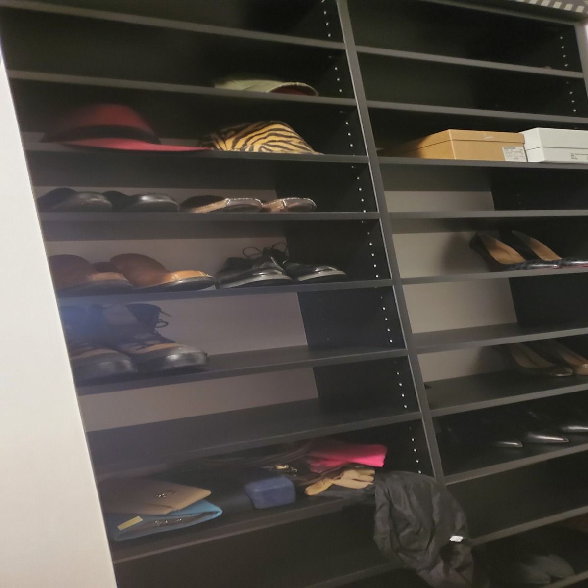 A black closet organizer filled with shoes, hats, and a box. Some shelves are empty.