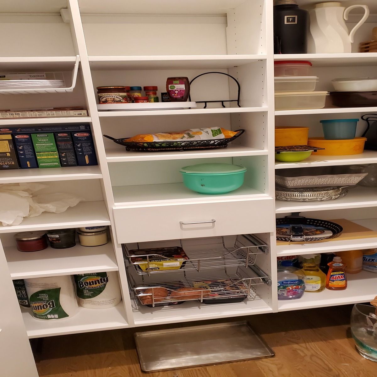 White pantry cabinet with shelves stocked with various food items, containers, and cookware.