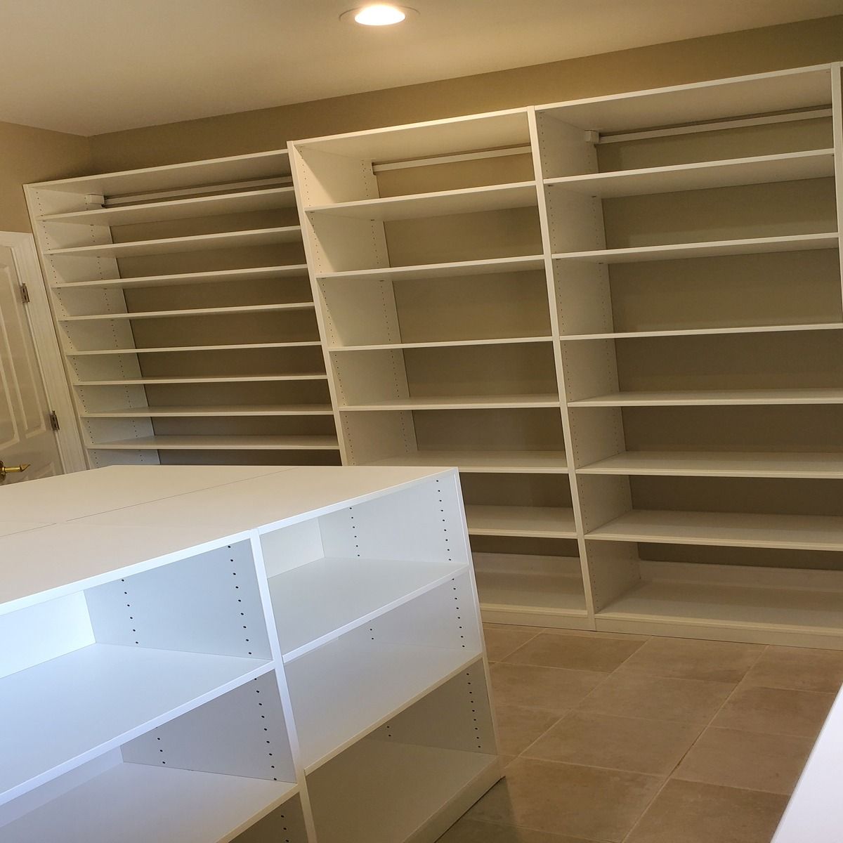 White built-in closet with shelves and hanging rods. Sections offer ample storage space for clothes and accessories.