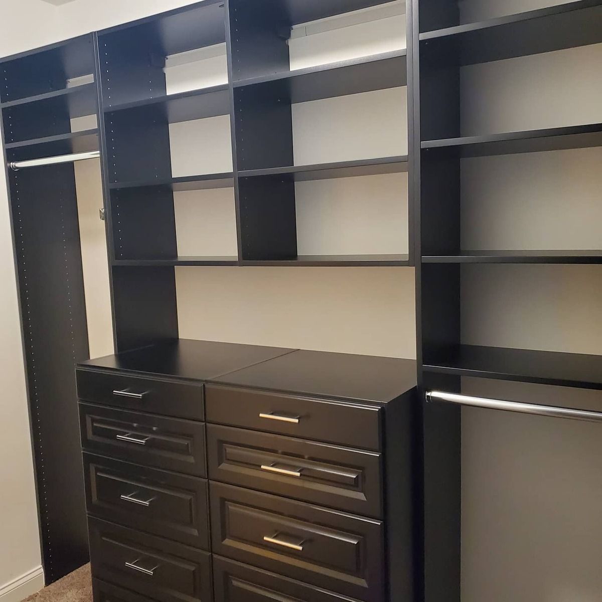 Dark custom closet organization with drawers, shelves, and hanging rods.