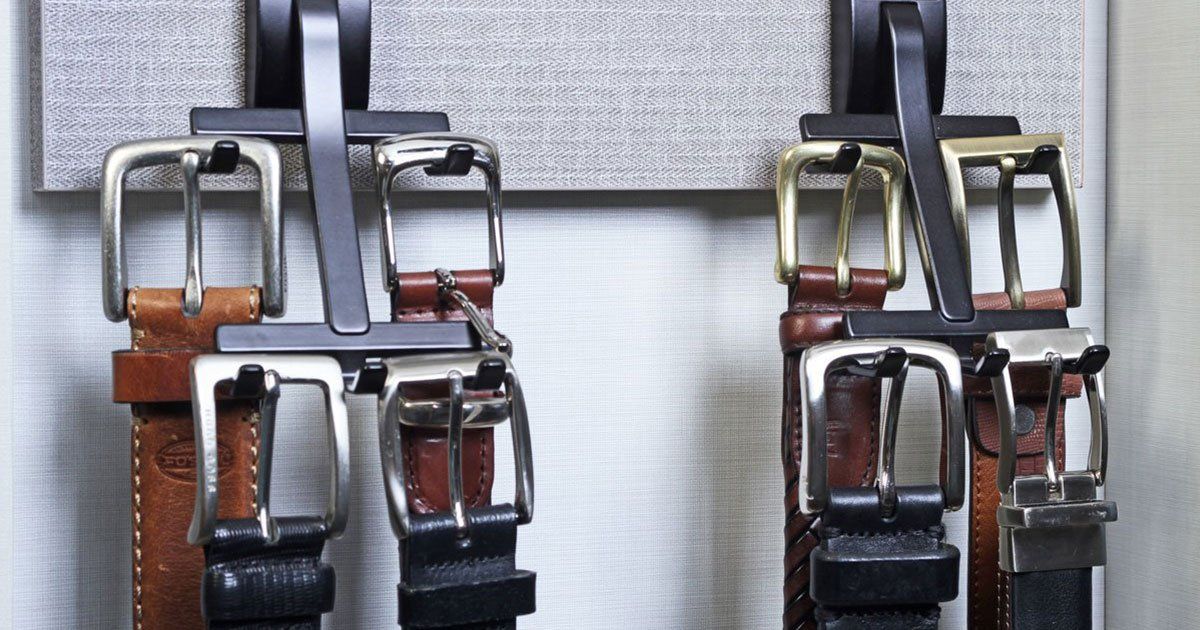 A bunch of belts are hanging on a rack on a wall.