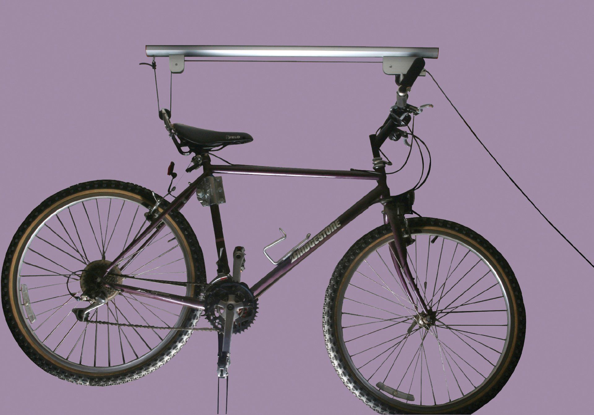 A bicycle is hanging from a ceiling with a purple background