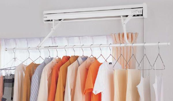 A bunch of clothes are hanging on a rack in a room.