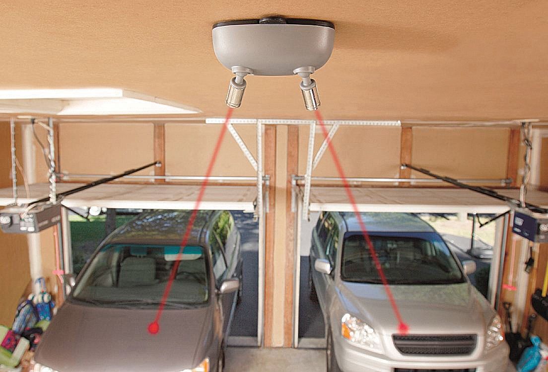 Two cars are parked in a garage with a garage door opener