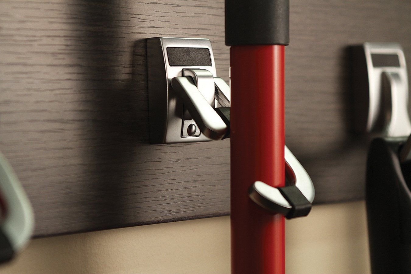 A red mop is attached to a hook on a wall