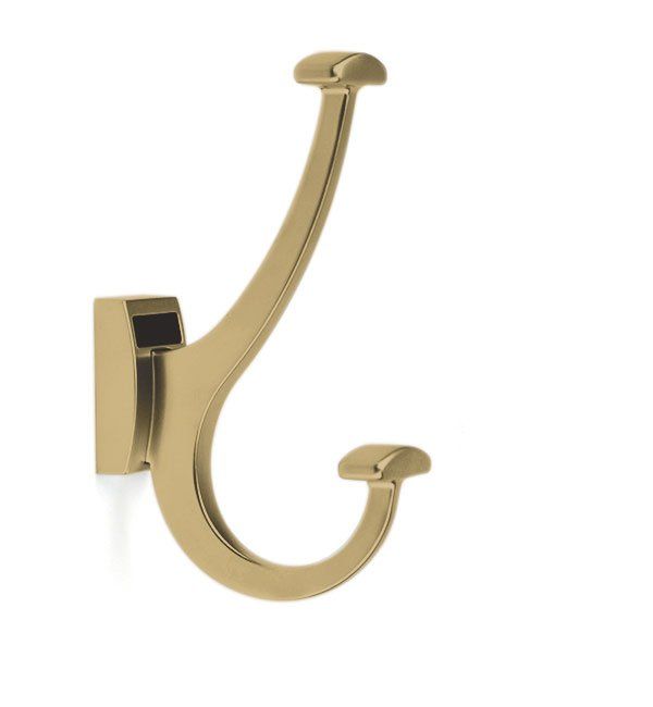 A gold coat hook on a white wall
