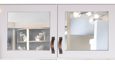 A white cabinet with two mirrored doors and a shelf with shoes on it.