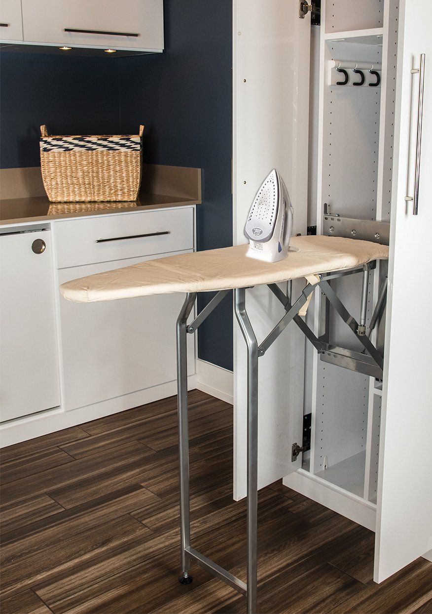 An ironing board is built into a cabinet in a laundry room.