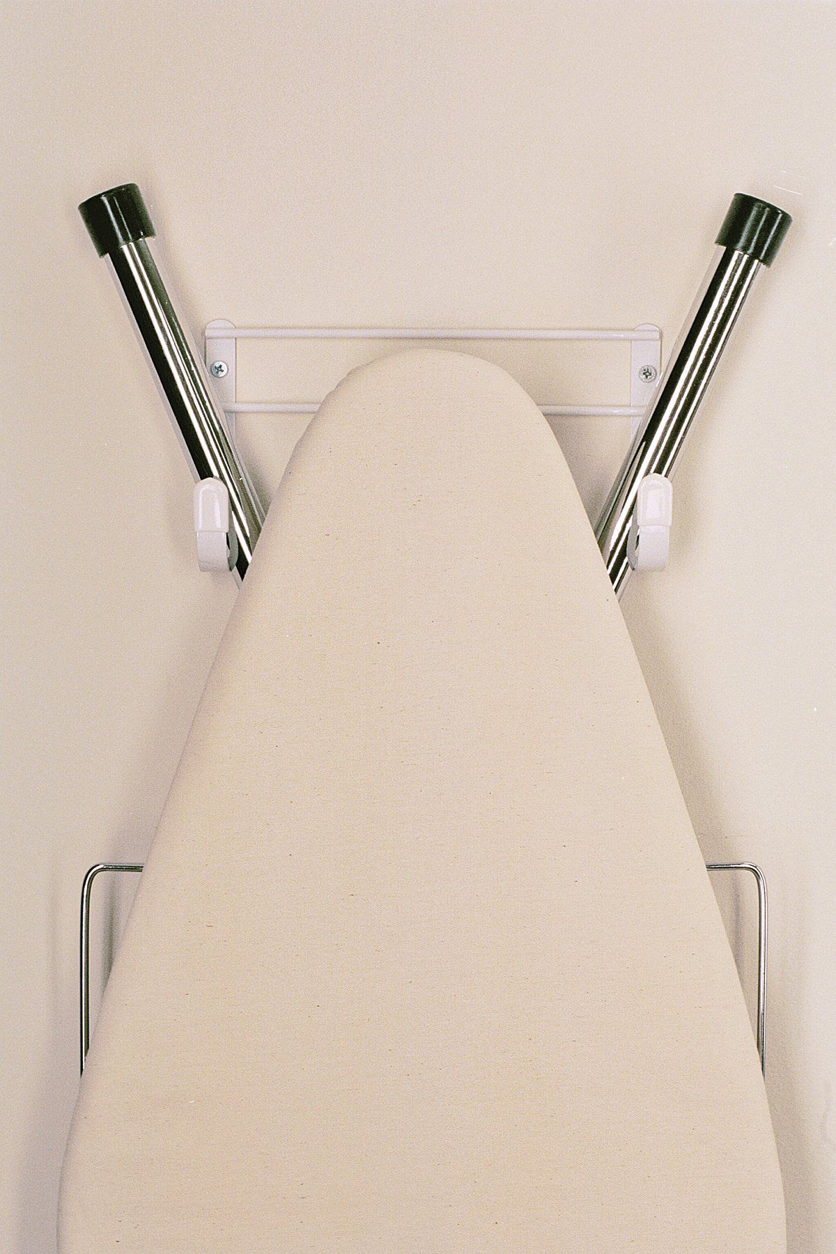An ironing board is attached to a wall with hooks