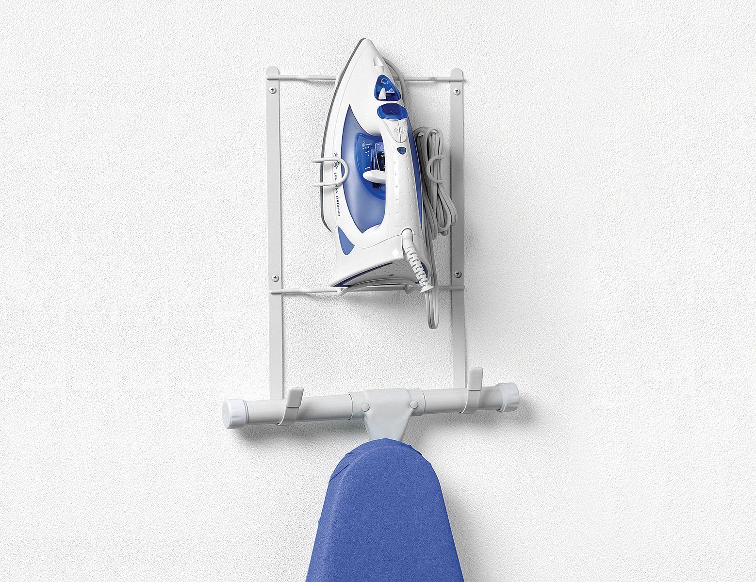 An iron is hanging on a wall next to an ironing board.