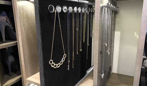A closet filled with lots of necklaces hanging on a rack.