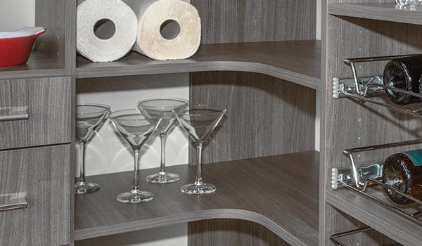 A corner of a cabinet with wine bottles and martini glasses.