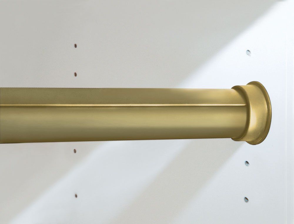 A brass shower curtain rod is hanging on a white wall.