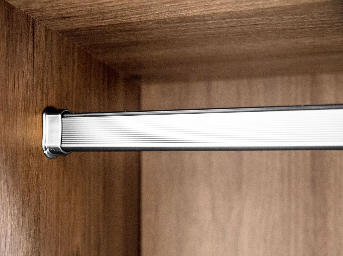 A close up of a metal bar in a wooden wardrobe.