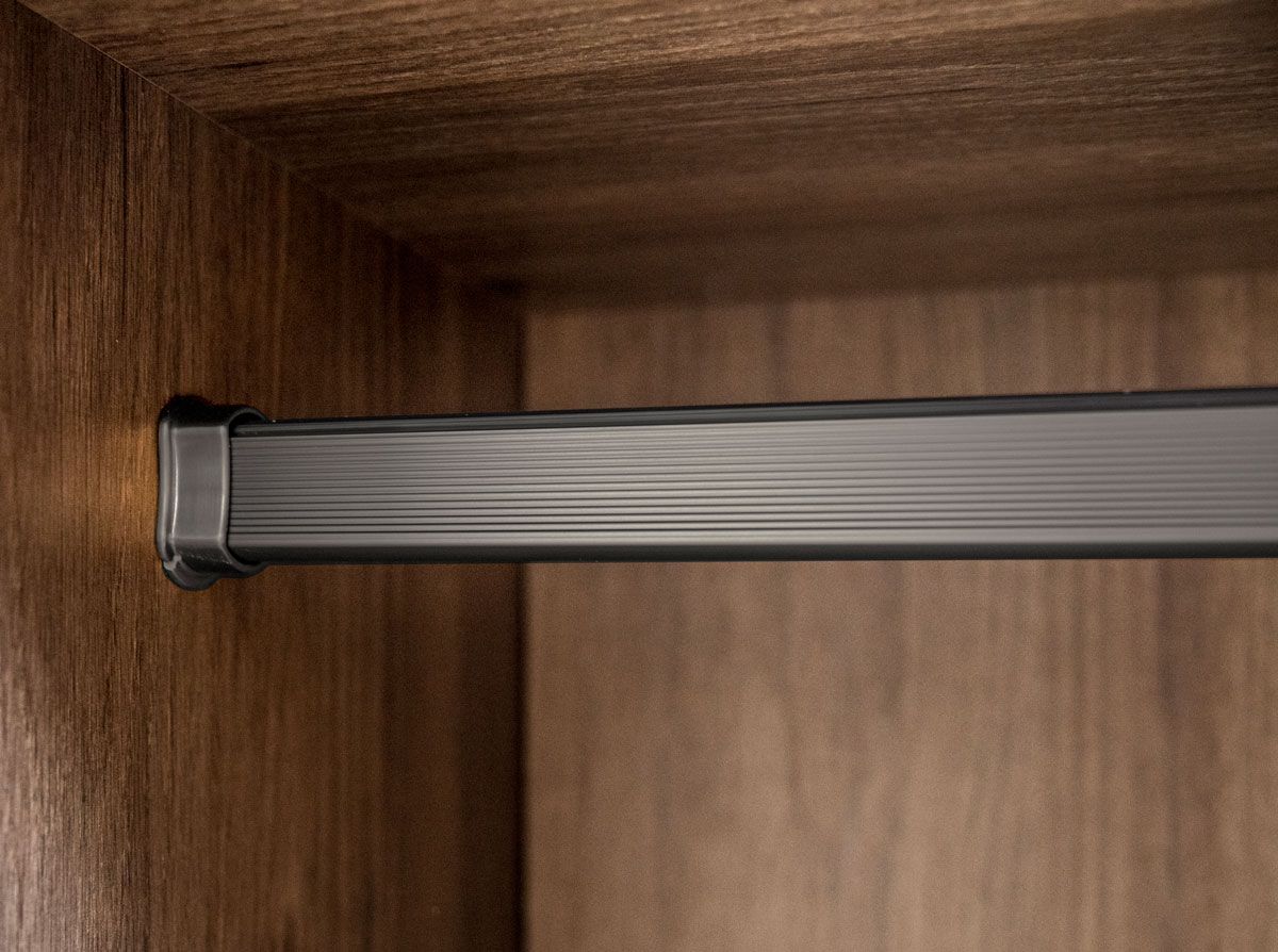 A close up of a metal rail in a wooden wardrobe.