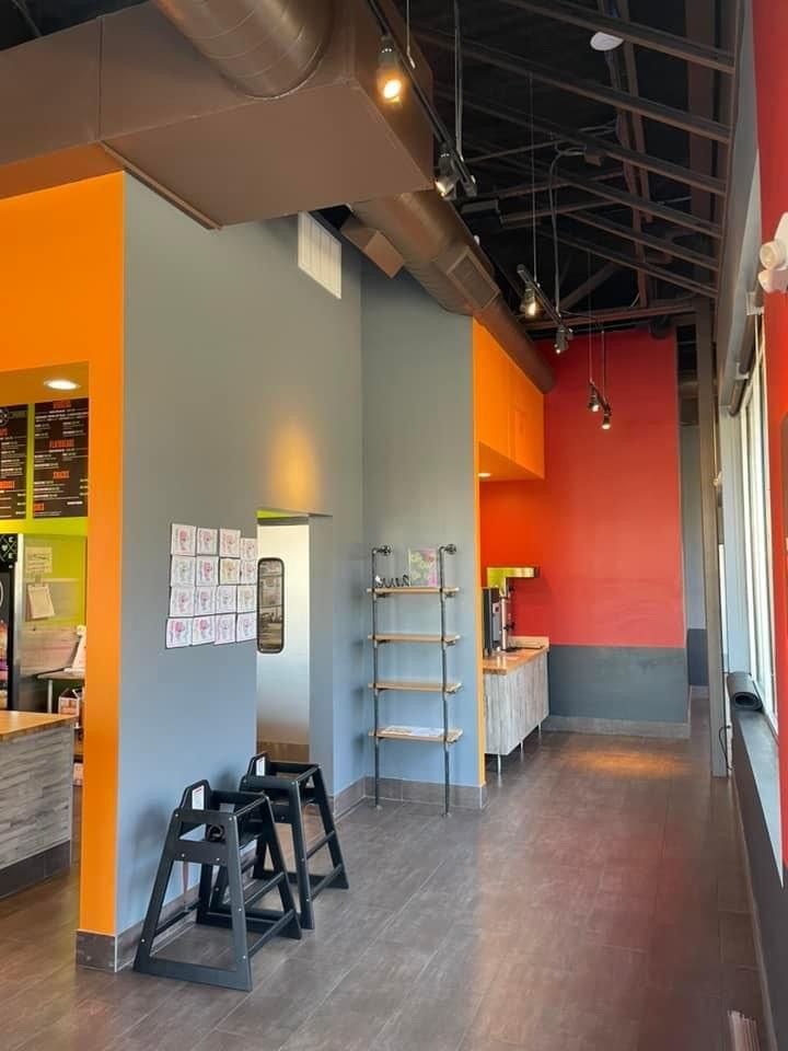A restaurant with a long hallway and a few chairs on the floor.