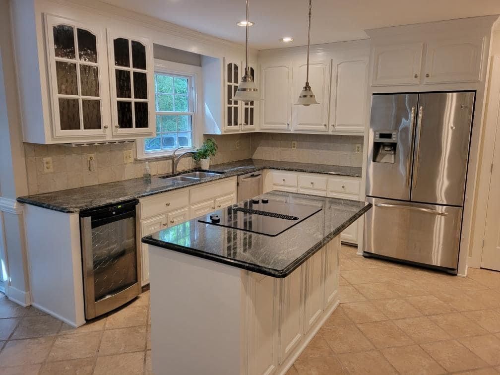 a kitchen with white cabinets , granite counter tops , stainless steel appliances and a large island .