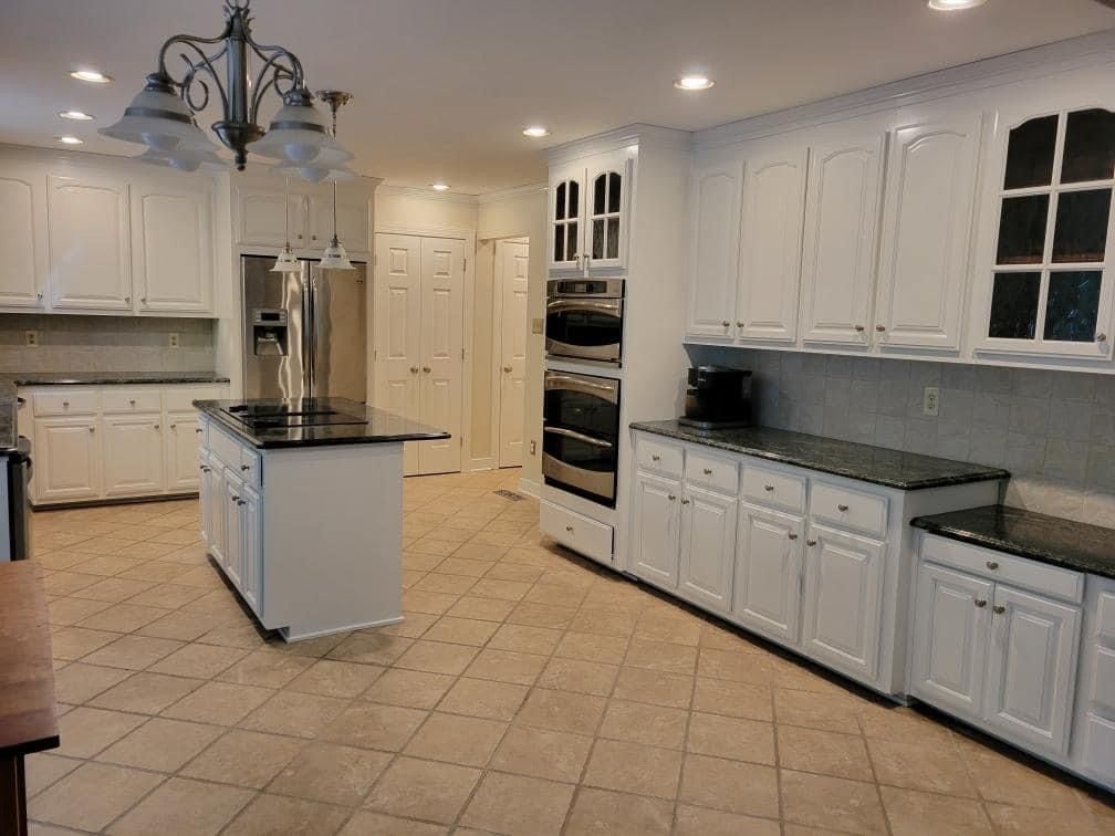 a kitchen with white cabinets and black counter tops