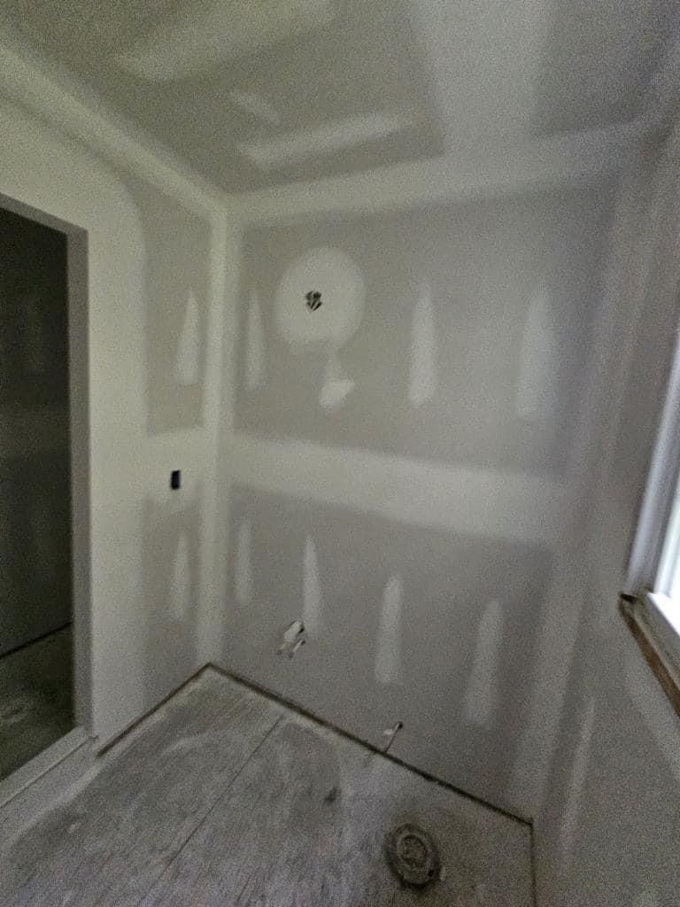 A room with drywall on the walls and a window.