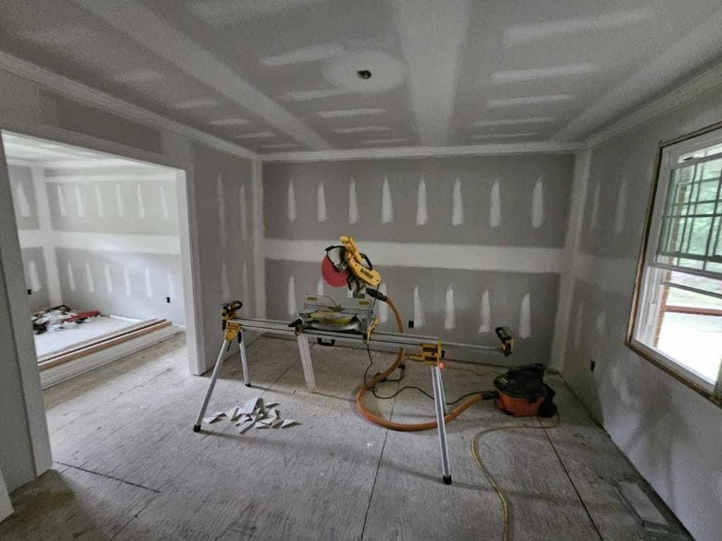 A room with drywall walls and a table saw in it.