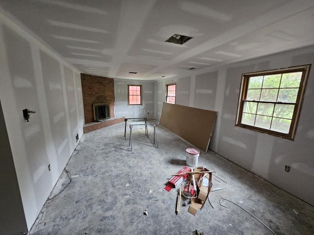 A living room is being remodeled with drywall and a fireplace.