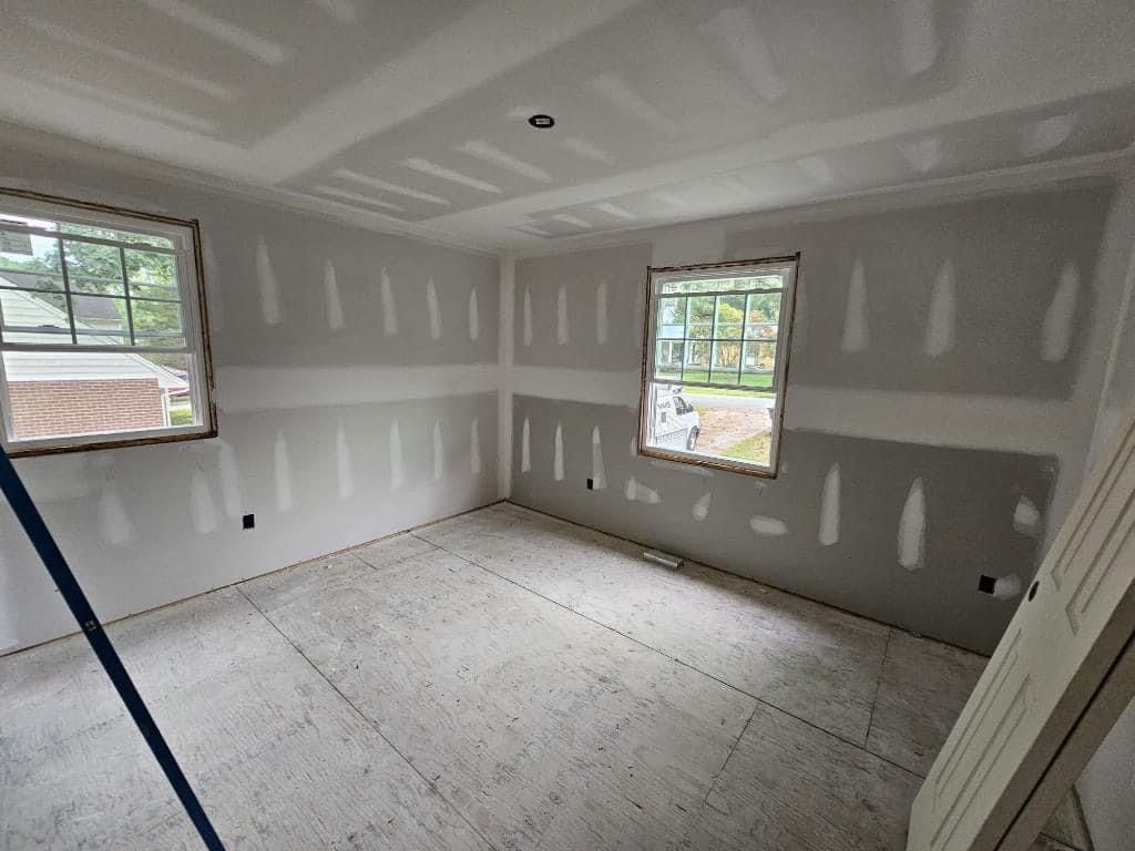 A room that is being remodeled with drywall and windows.