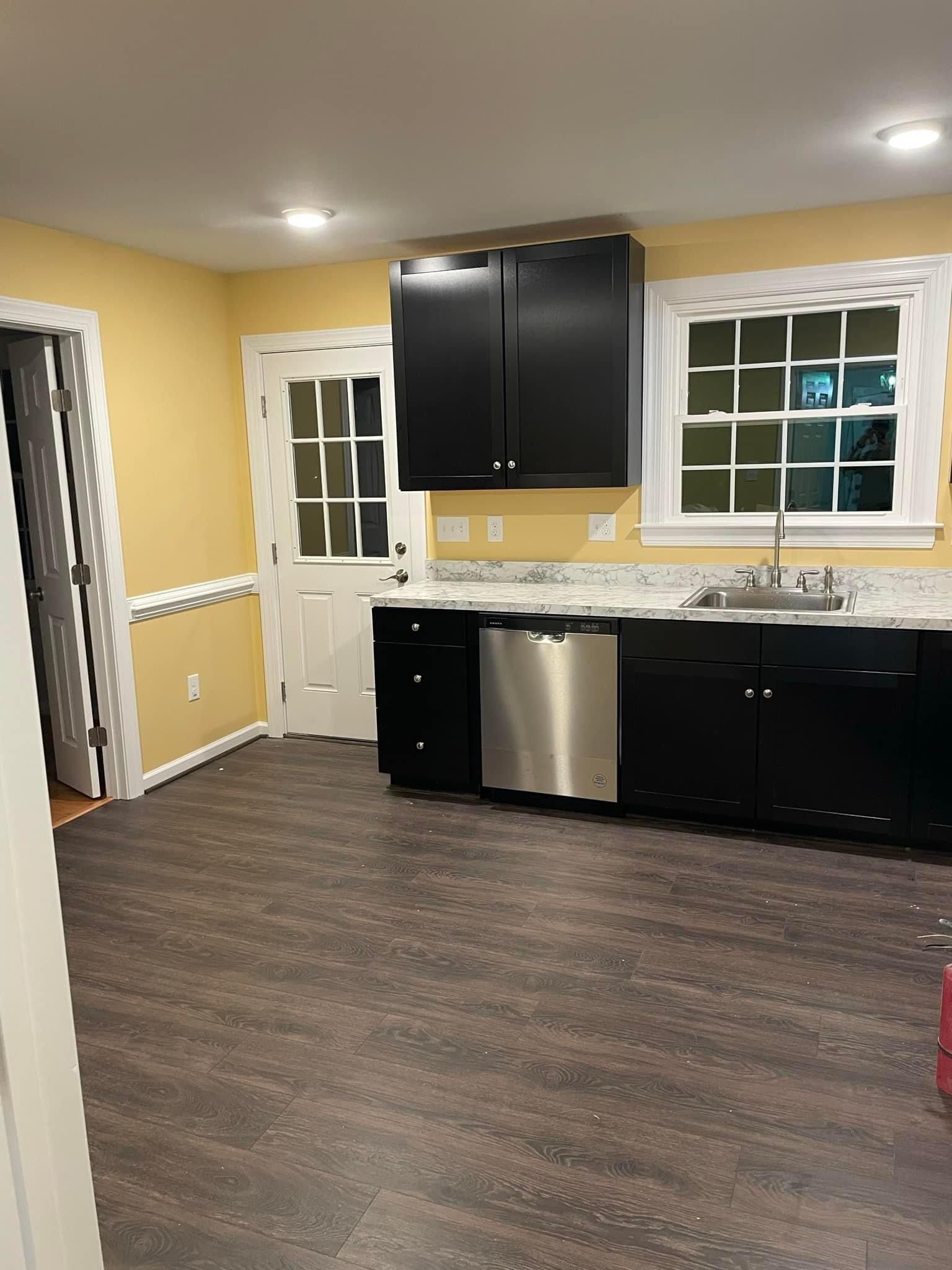 A kitchen with black cabinets , stainless steel appliances , and a sink.