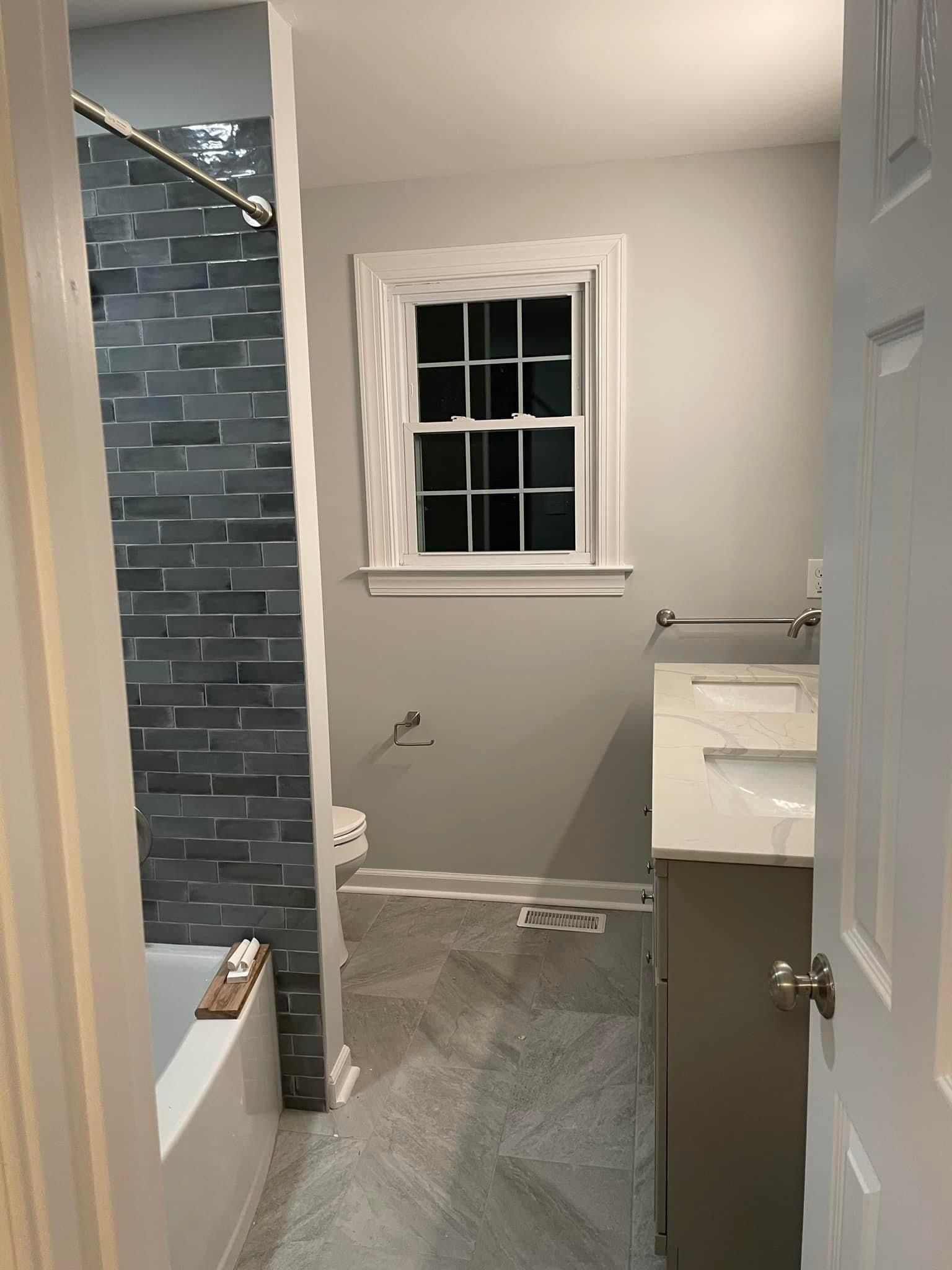 A bathroom with a sink , tub , shower and window.