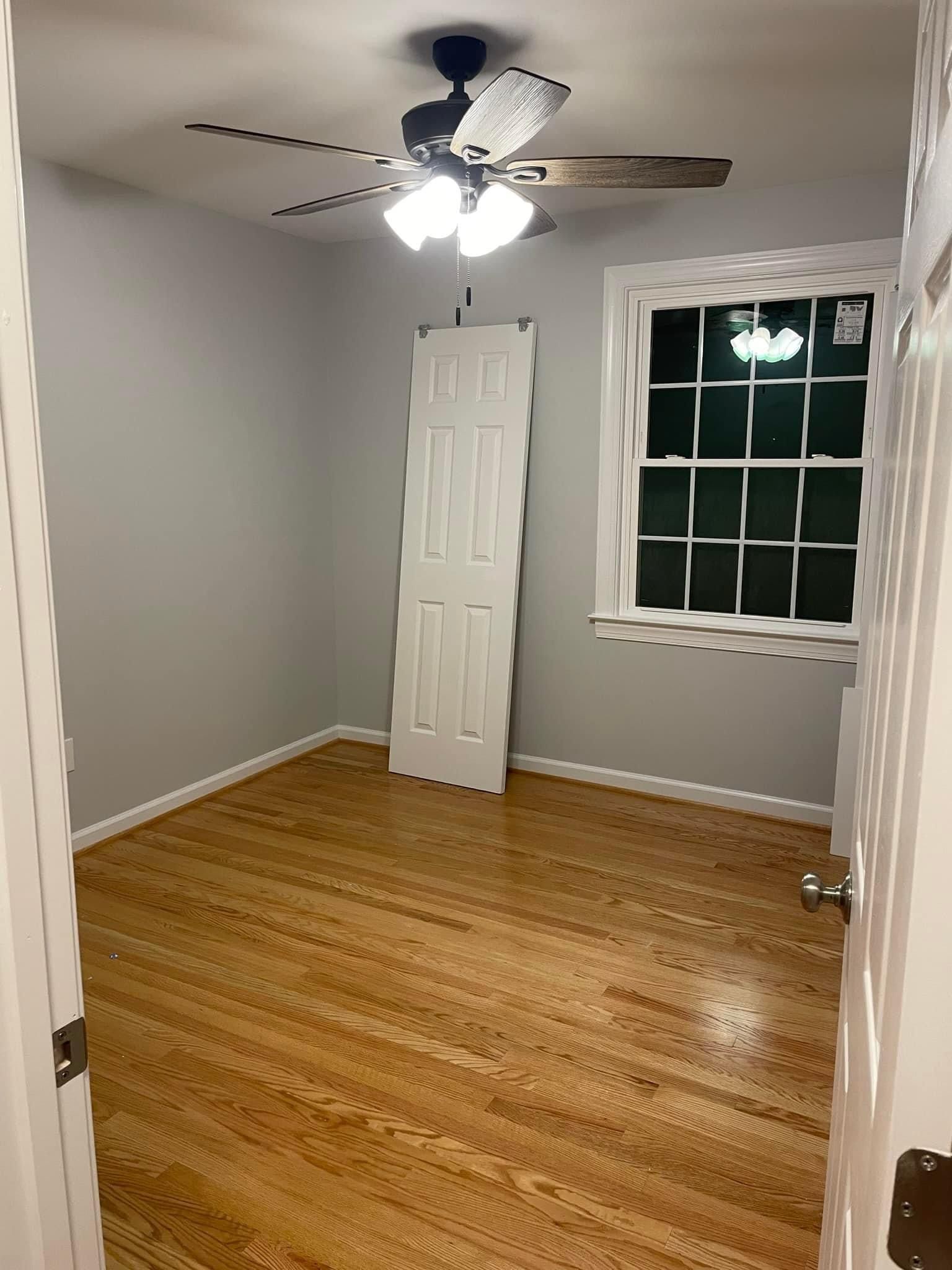 An empty room with hardwood floors and a ceiling fan.