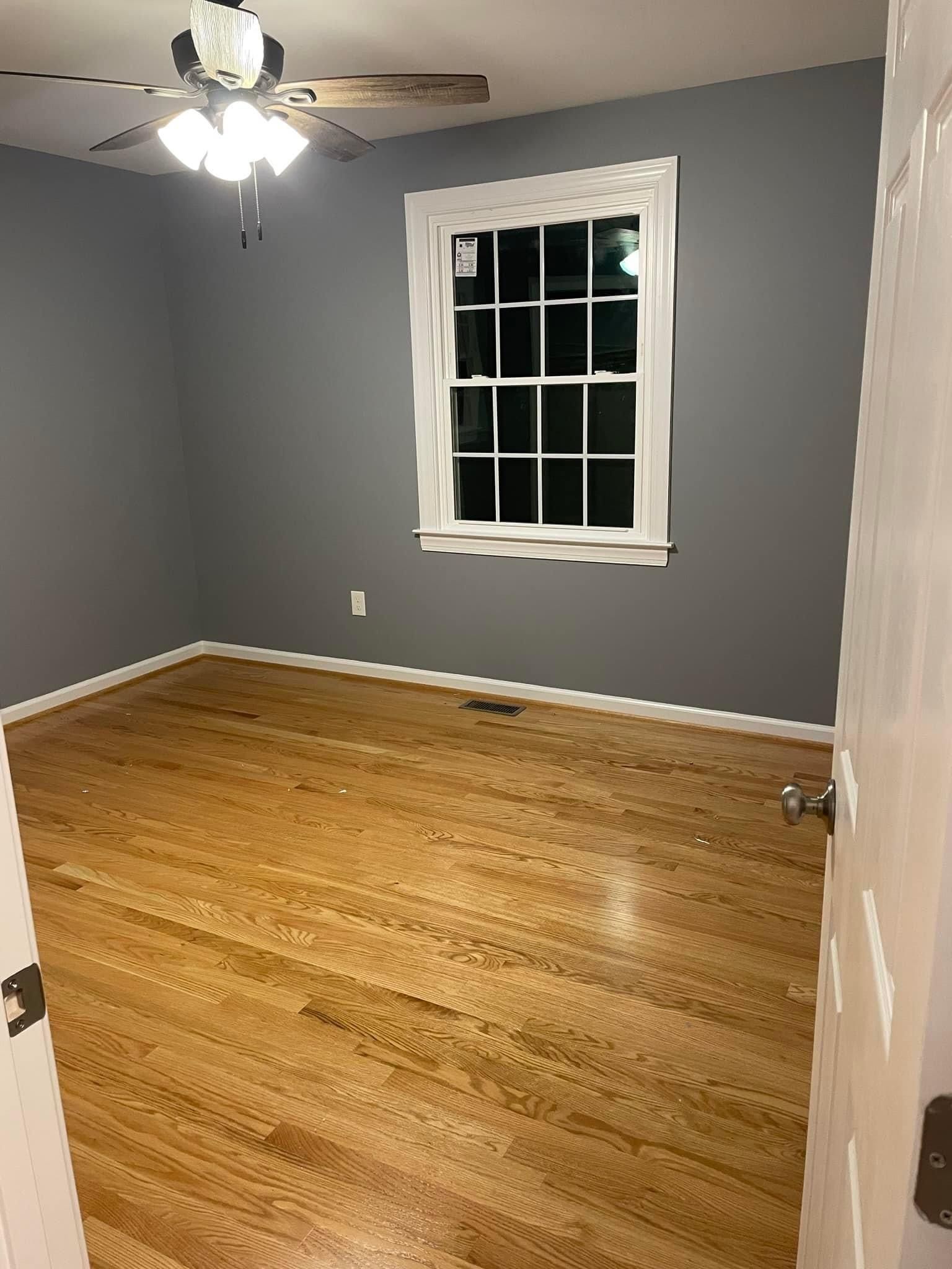 An empty room with hardwood floors and a ceiling fan.