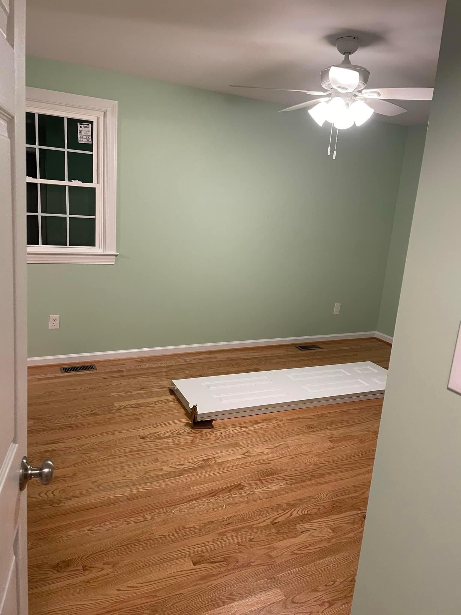 An empty room with a ceiling fan and a window.