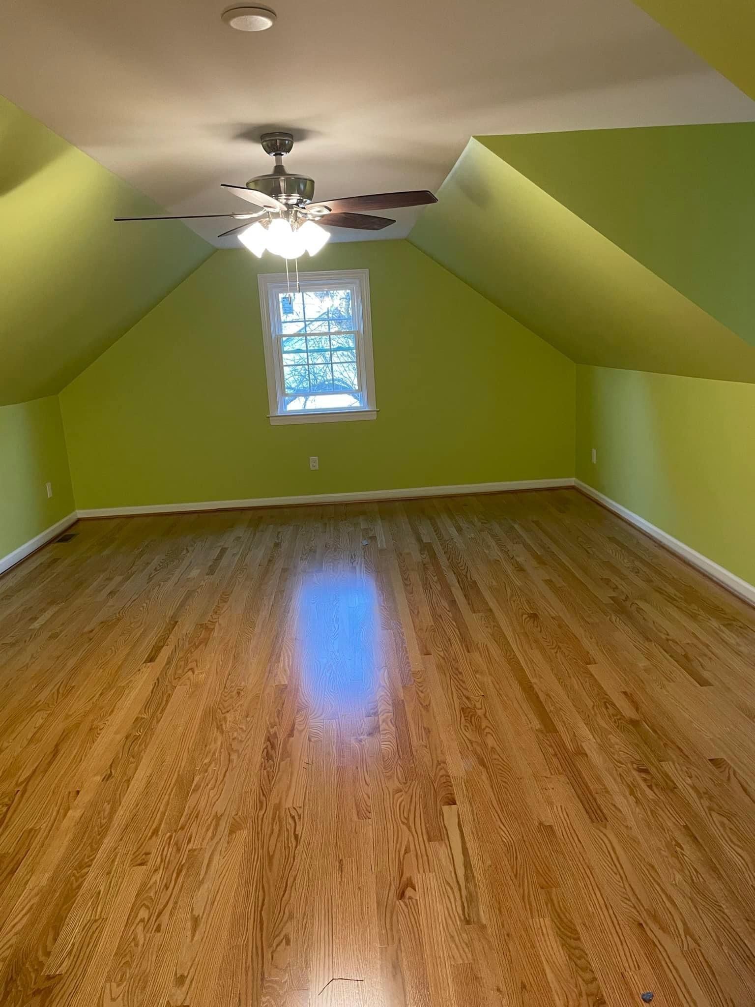 An empty room with hardwood floors and a ceiling fan.