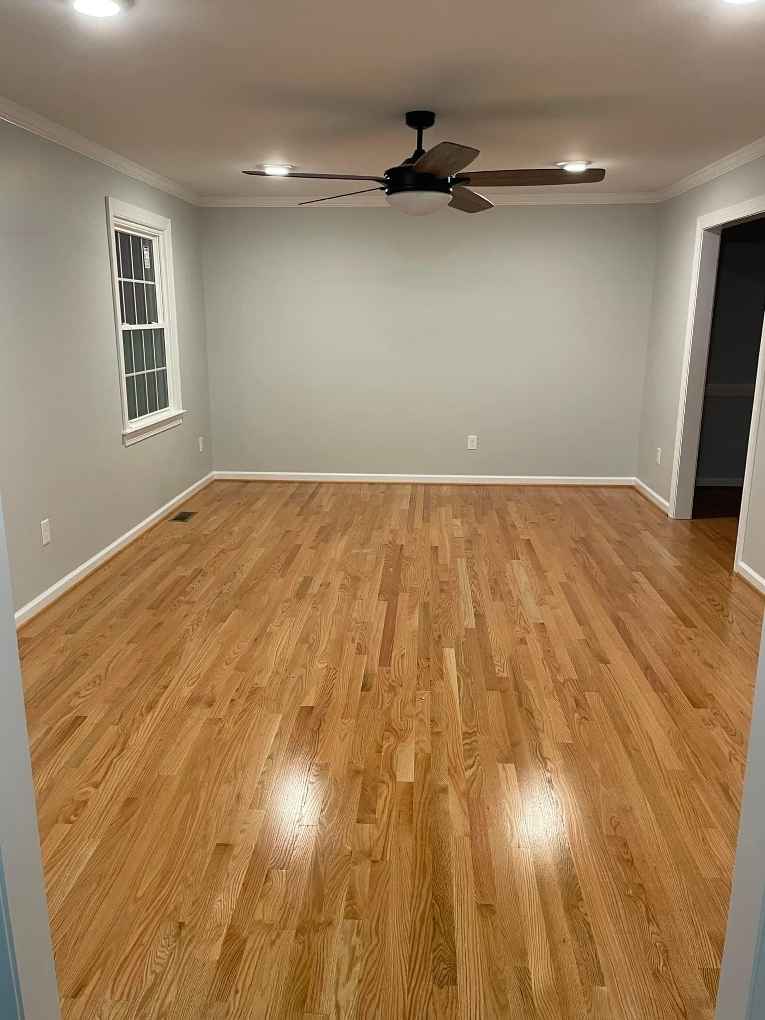 A living room with hardwood floors and a ceiling fan.
