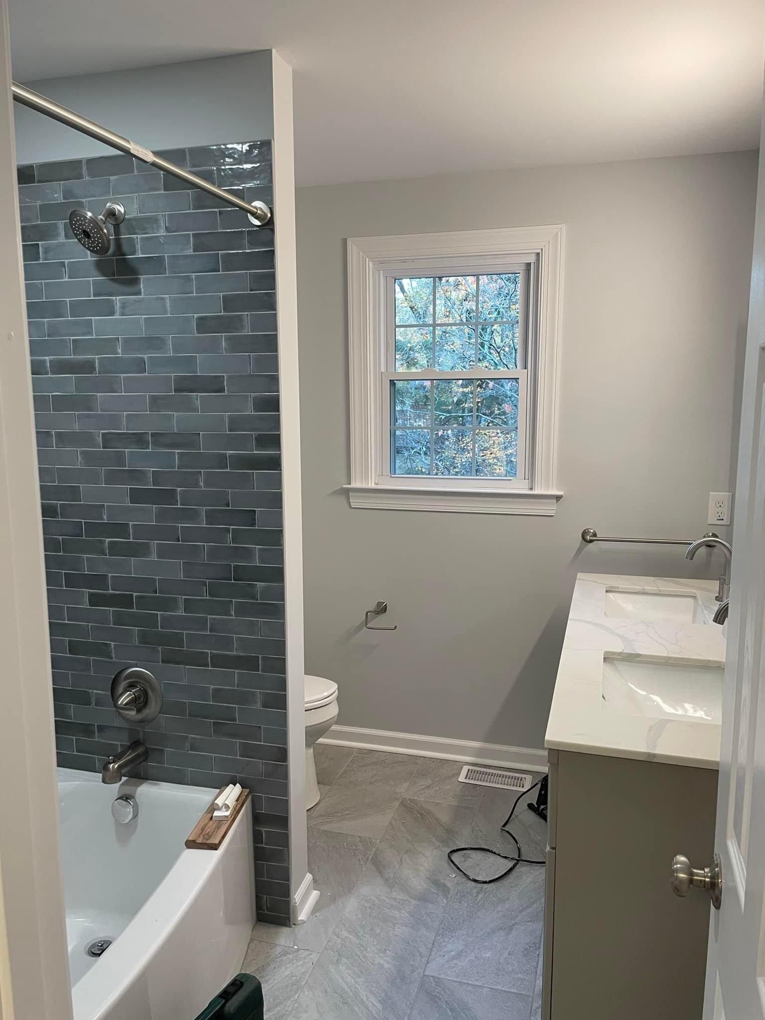 A bathroom with a bathtub , sink , shower and window.