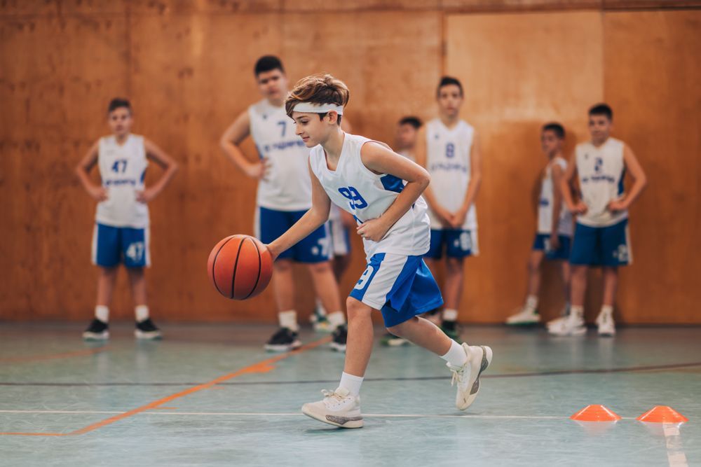 A young boy is dribbling a basketball during a basketball game.