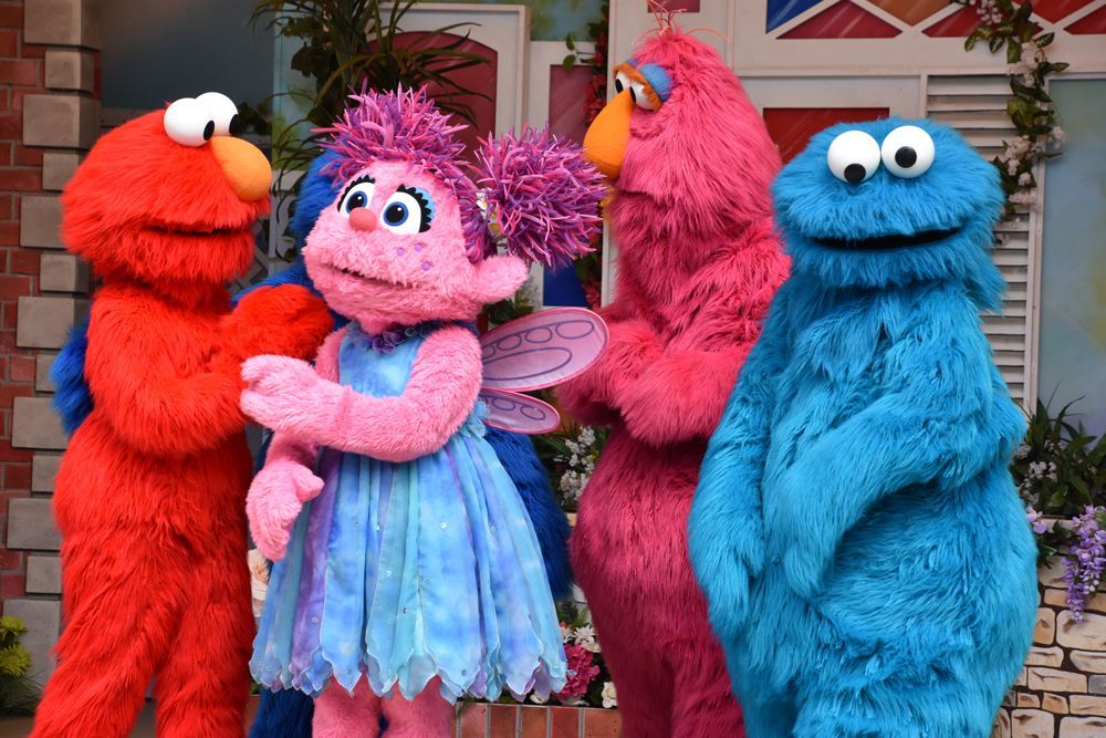 A group of sesame street characters standing next to each other
