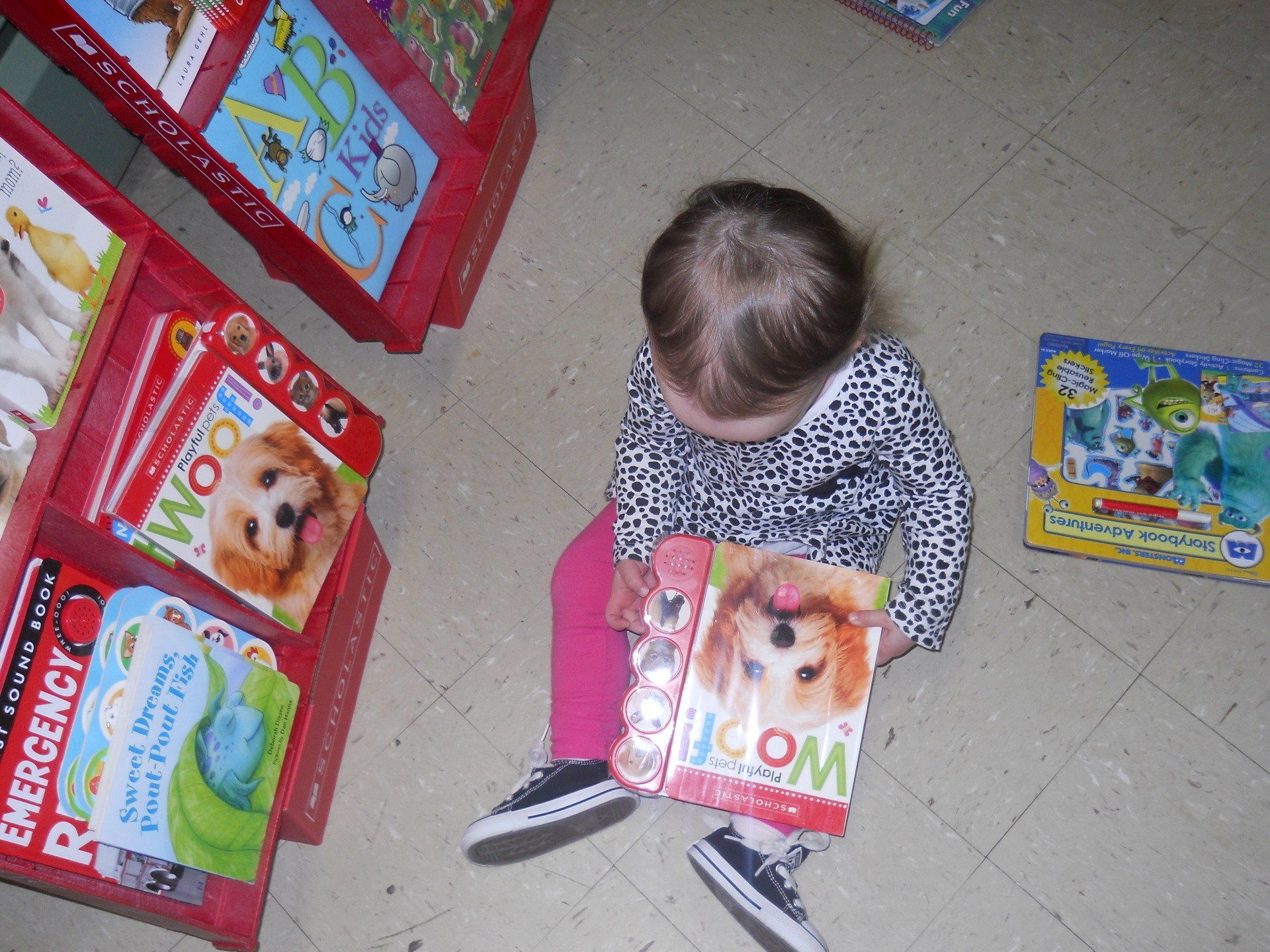 A little girl is reading a book called woof