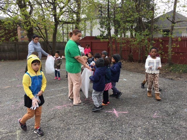 A group of children are playing with a woman in a green shirt